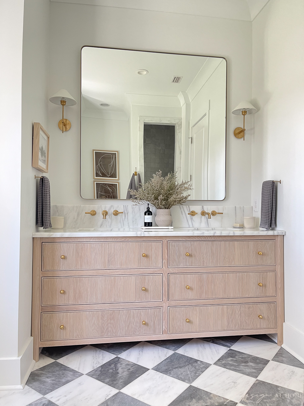 white oak vanity in master bath with marble countertops and harlequin checkered marble floors and brass fixtures