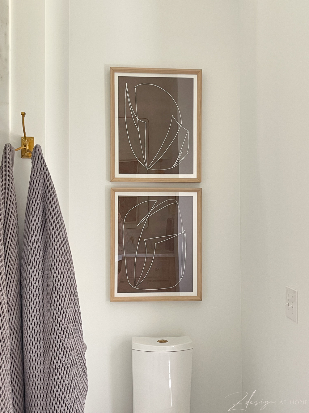 brown and white abstract art with white oak frame hanging over toilet 