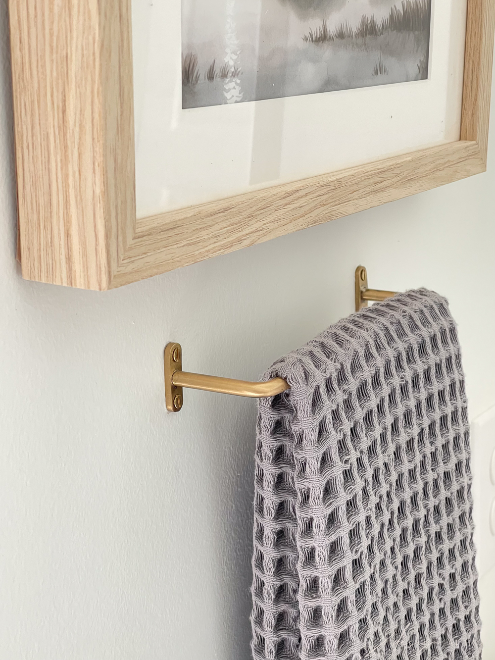 simple modern brass hand towel bar with gray waffle weave hand towel and level 5 sheet rock finish